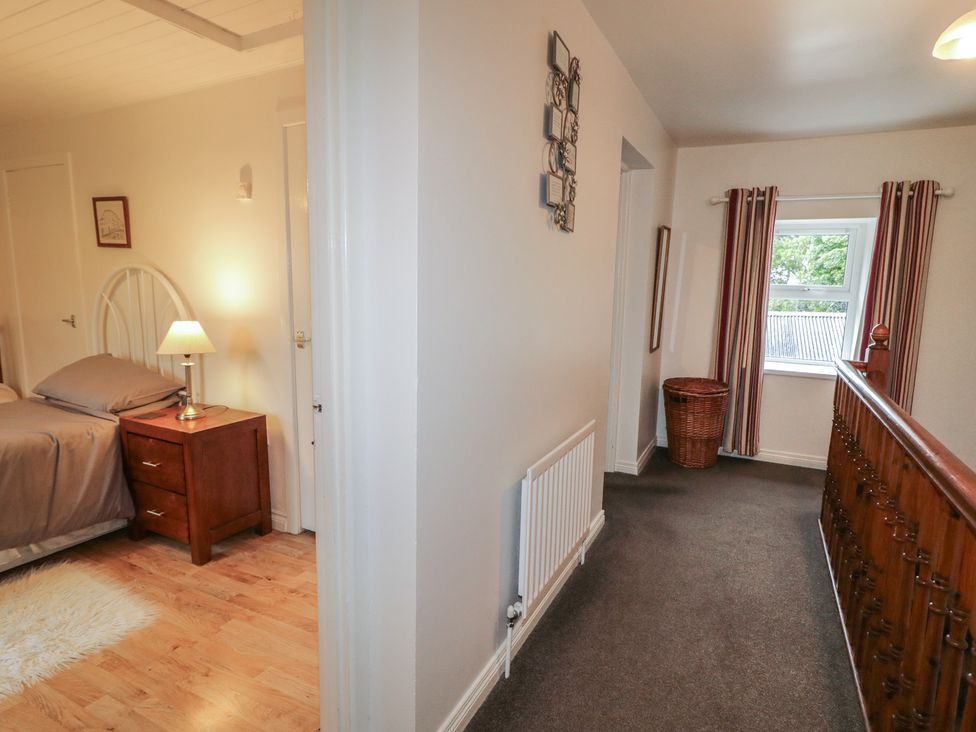 A hallway with a door to a bedroom and a window with curtains at Shaws Hill Farmhouse, Kells, County Antrim