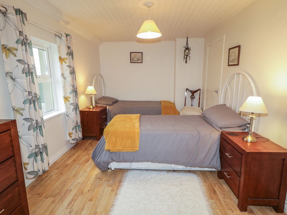 A bedroom with two beds and bedside tables at Shaws Hill Farmhouse in Kells, County Antrim