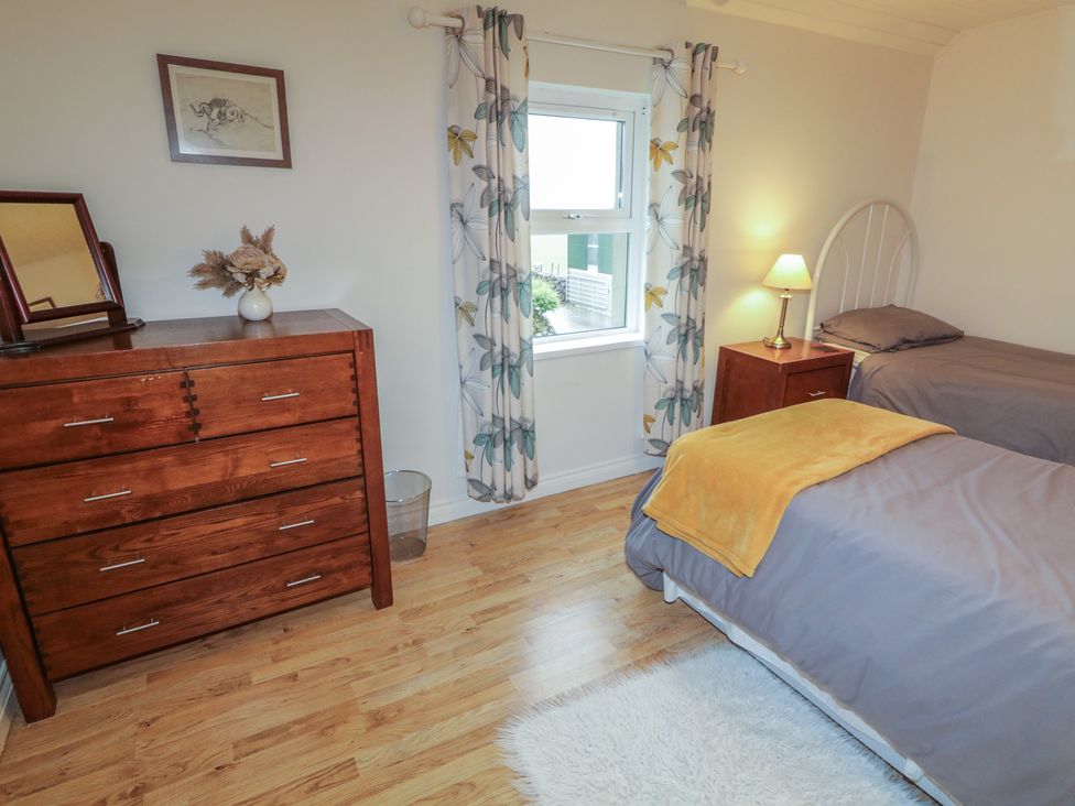 A bedroom with a bed, dresser, and window at Shaws Hill Farmhouse in Kells, County Antrim