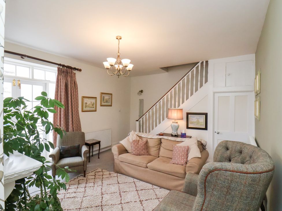 A living room with a sofa, chairs, and a lamp at 20A St Hilda's in Whitby