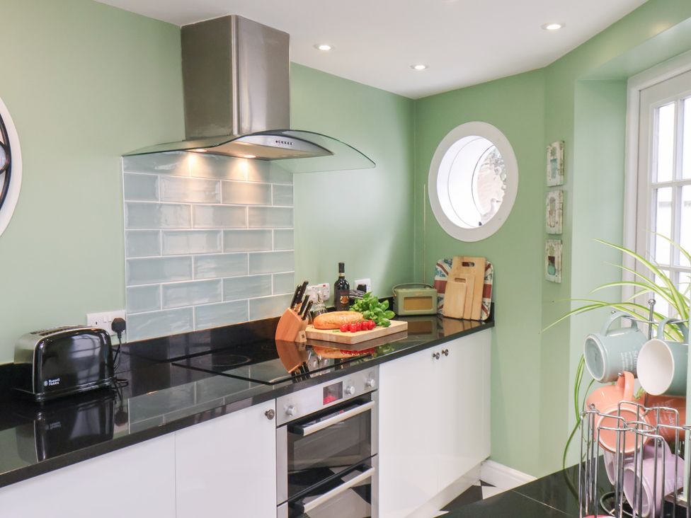 A kitchen with a black countertop and appliances at 20A St Hilda's in Whitby