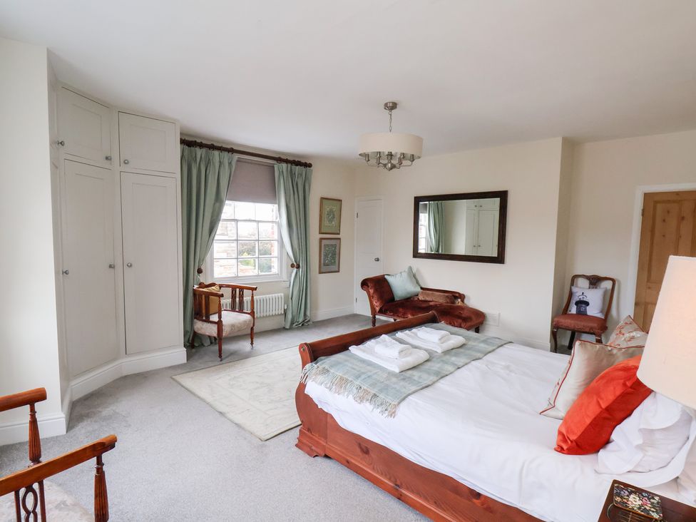 A bedroom with a bed, armchair, and window at 20A St Hilda's in Whitby