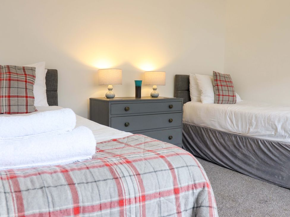 A bedroom with two beds and a dresser at Glyn Morfa in Harlech