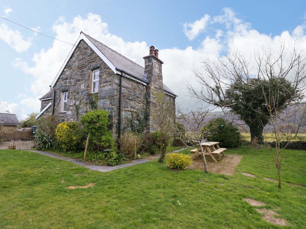 A stone house with a garden and a picnic table at Glyn Morfa in Harlech