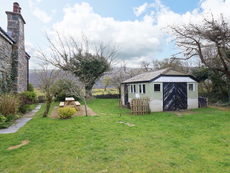 A garden with a shed and picnic table at Glyn Morfa in Harlech