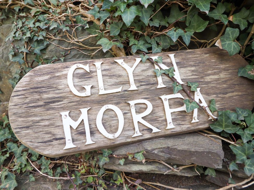 A wooden sign reading Glyn Morfa surrounded by ivy at Glyn Morfa in Harlech