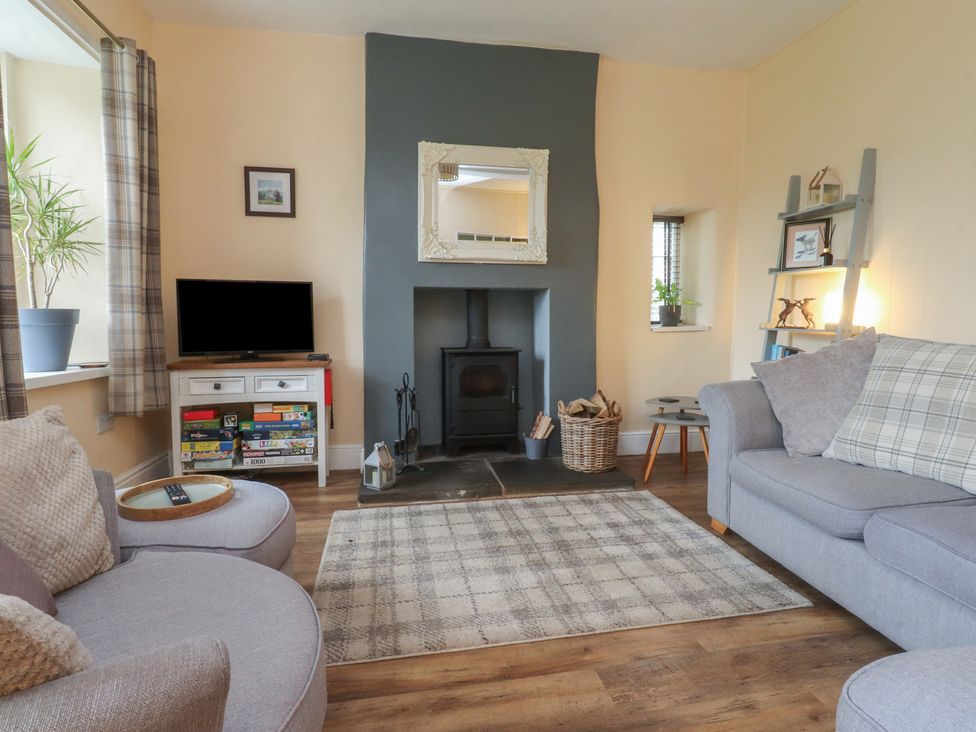 A living room with a sofa, television, and fireplace at Glebe Cottage Broughton near Skipton