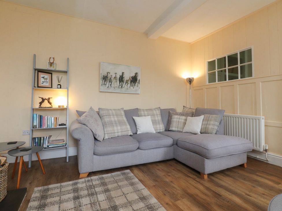 A living room with a sofa and bookshelves at Glebe Cottage Broughton near Skipton