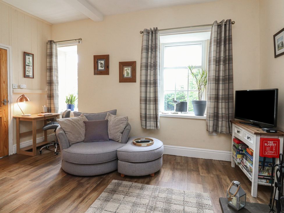 A living room with a sofa and desk at Glebe Cottage in Broughton near Skipton