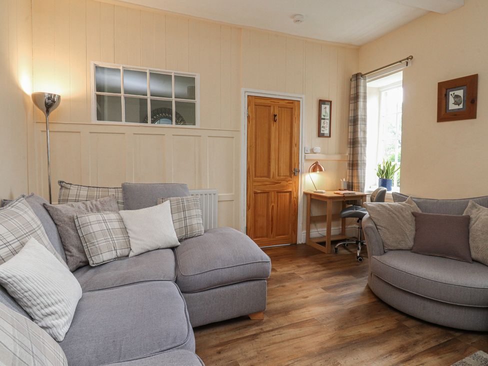 A living room with a sofa and desk at Glebe Cottage in Broughton near Skipton