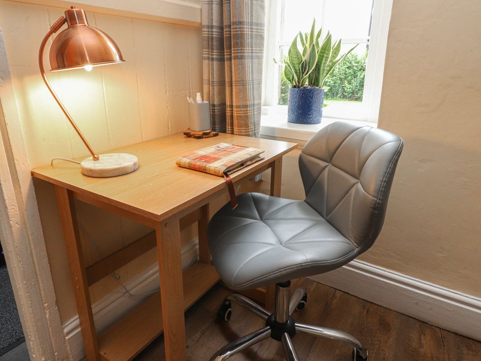 A workspace with a desk, chair, lamp, and a plant at Glebe Cottage in Broughton near Skipton