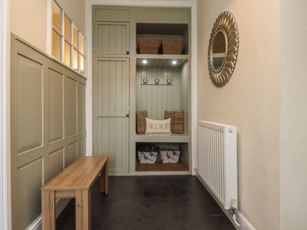 A hallway with a bench, mirror, and storage at Glebe Cottage Broughton near Skipton