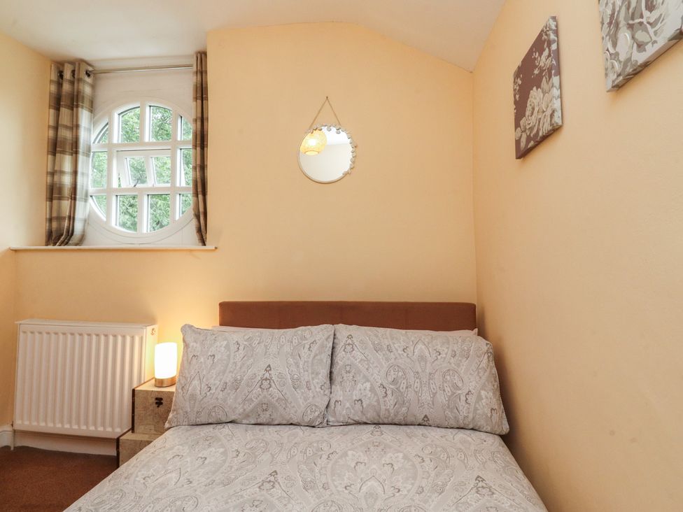 A bedroom with a bed beside a window and a lamp at Glebe Cottage Broughton near Skipton