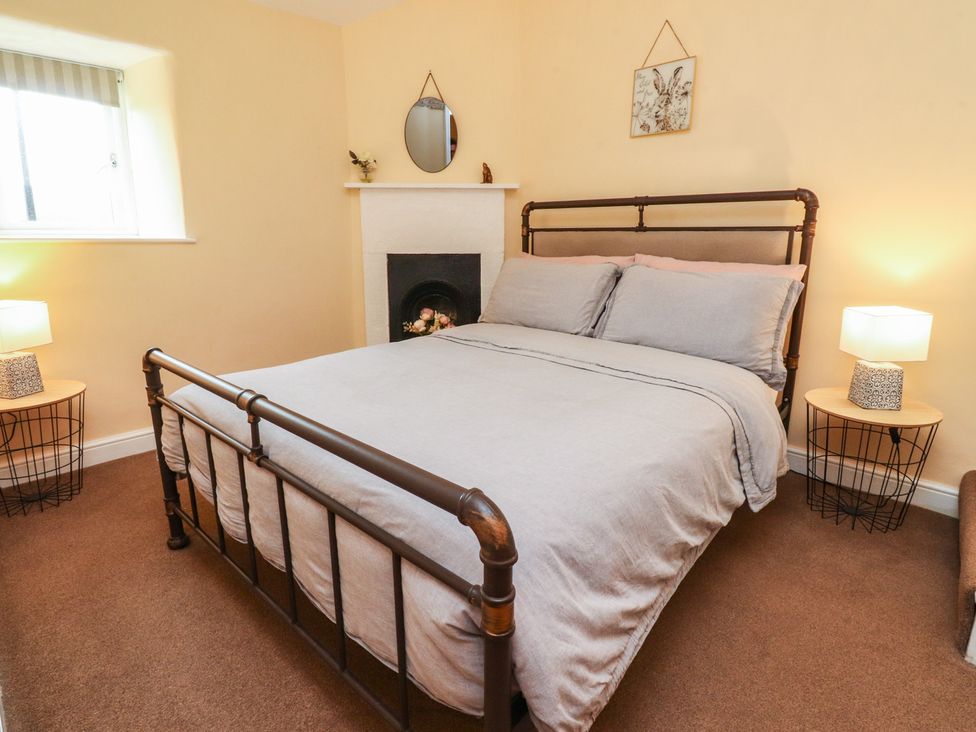 A bedroom with a bed and bedside tables at Glebe Cottage in Broughton near Skipton