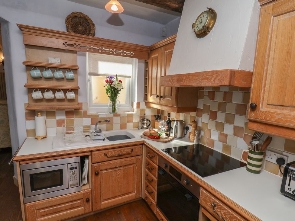 A kitchen with wooden cabinets and countertop at Cobbles House in Whitby