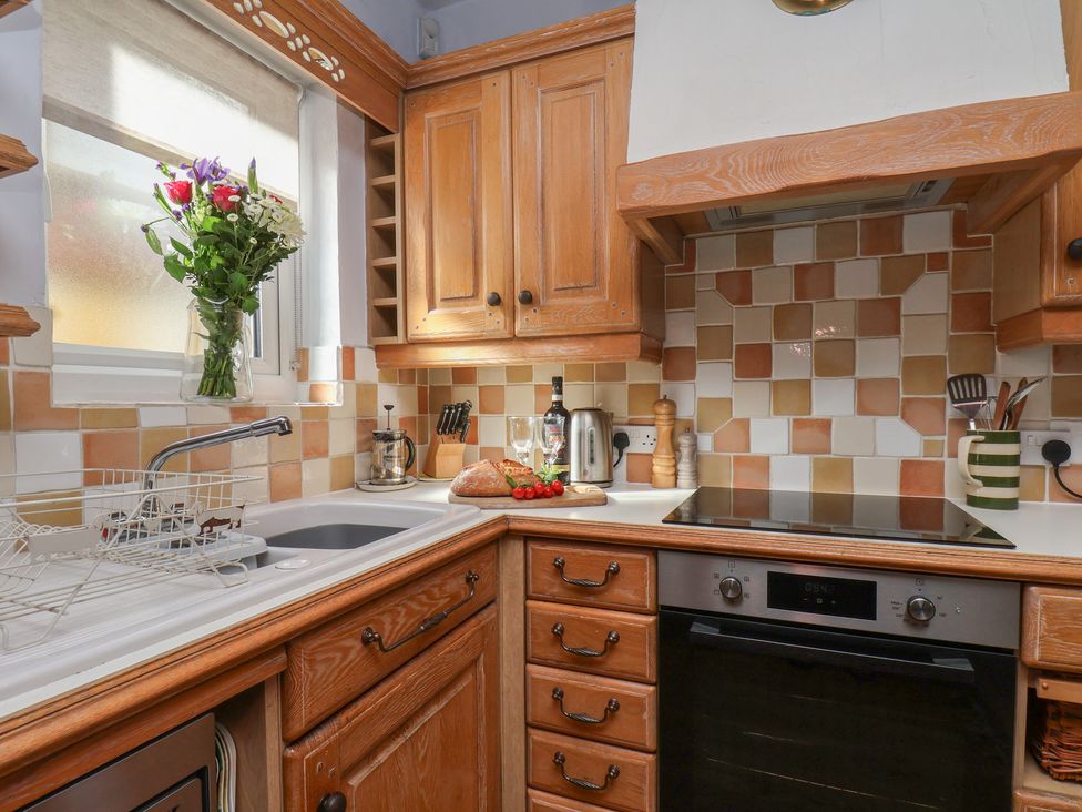 A kitchen with wooden cabinets and a sink at Cobbles House in Whitby