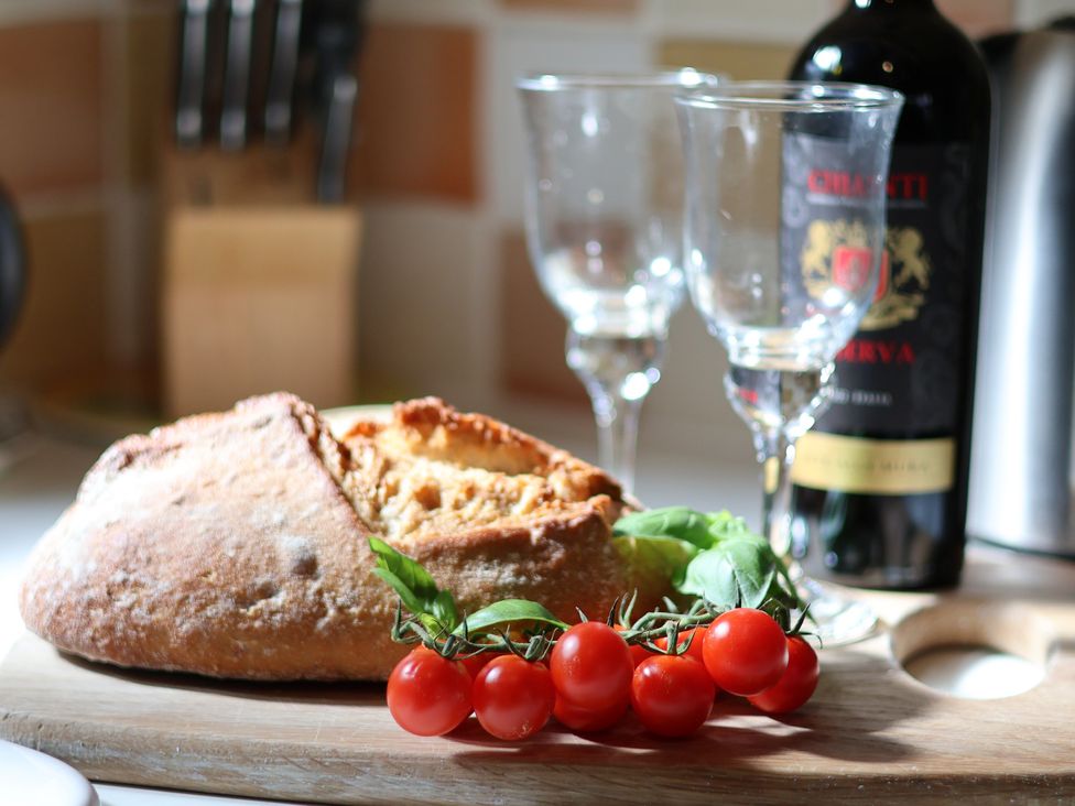 A bread loaf with wine, glasses, basil and tomatoes at Cobbles House in Whitby