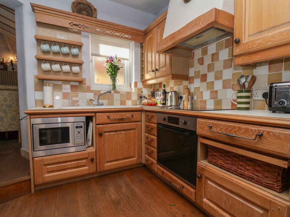 A kitchen with wooden cabinets and appliances at Cobbles House in Whitby