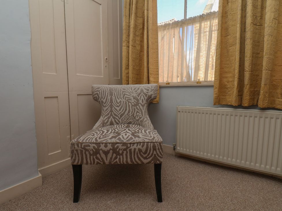 A chair near curtains and a radiator at Cobbles House in Whitby