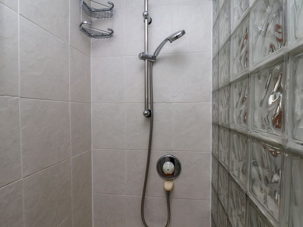 A shower area with a showerhead and shelf at Cobbles House in Whitby