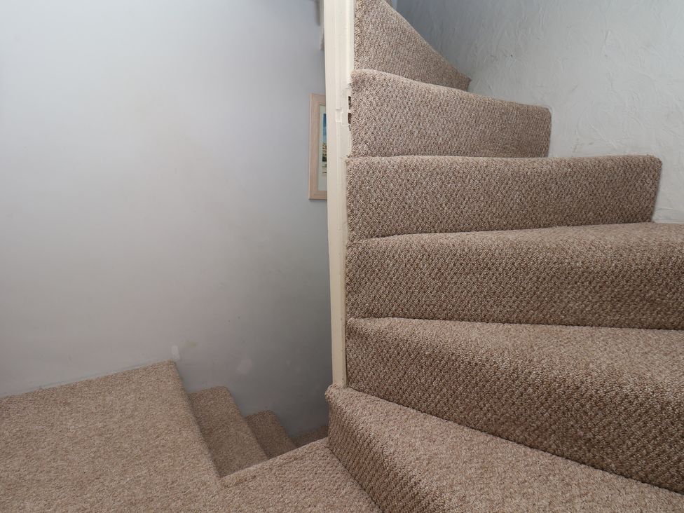 A staircase with carpet and a picture frame at Cobbles House in Whitby