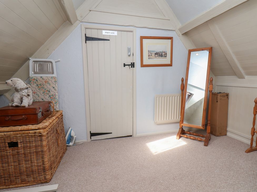An attic with a door, mirror, radiator, and storage at Cobbles House in Whitby