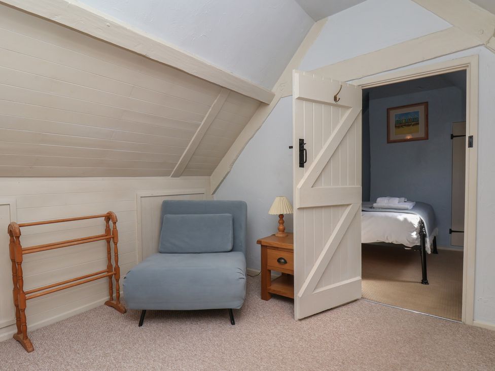 A bedroom with a chair and a small table at Cobbles House in Whitby