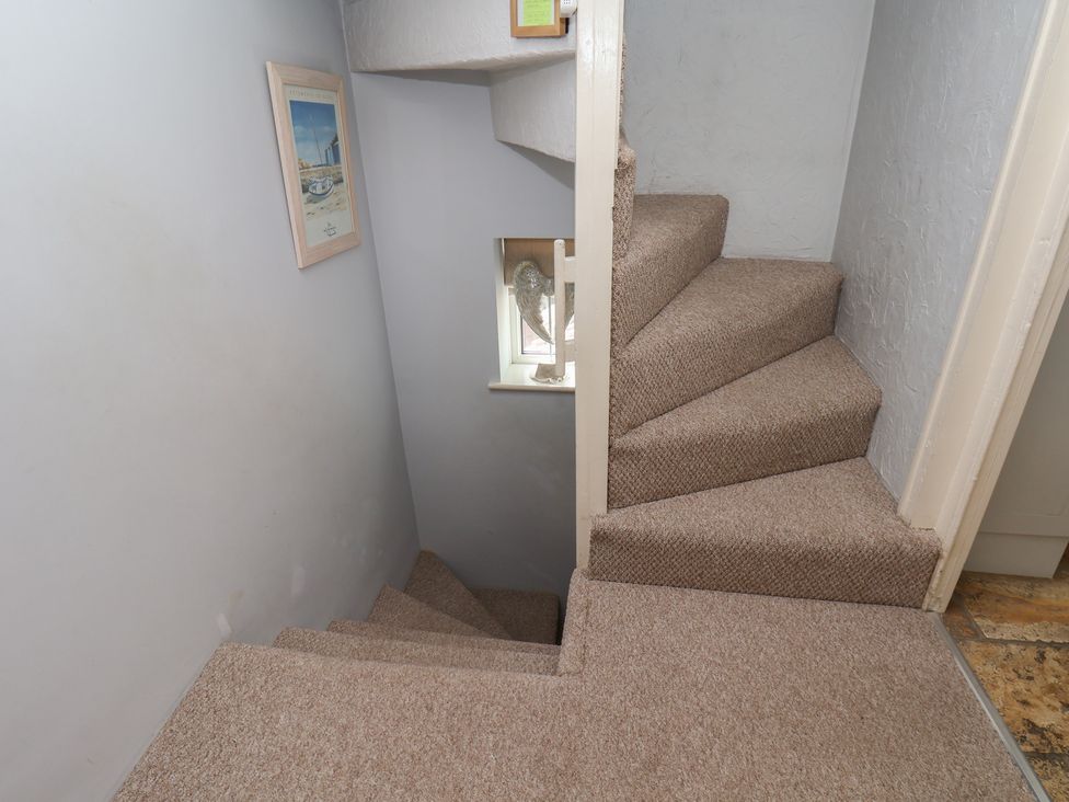 A staircase with carpet and a framed picture at Cobbles House in Whitby