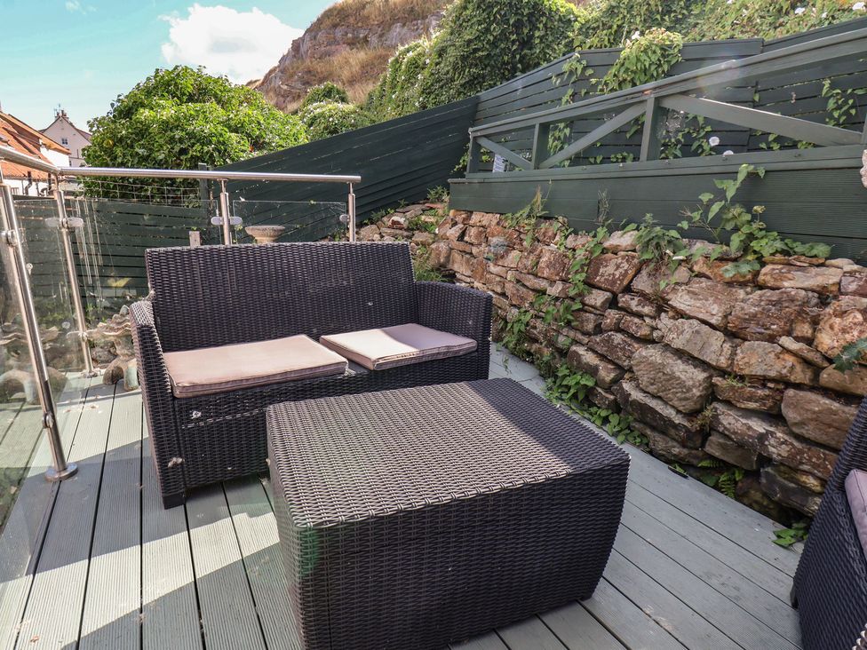 A garden with a sofa and coffee table at Cobbles House in Whitby