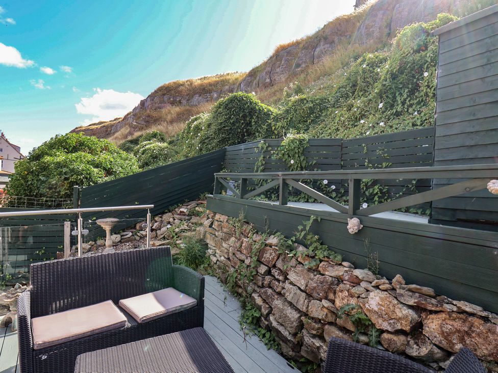 An outdoor space with benches and a stone wall at Cobbles House in Whitby