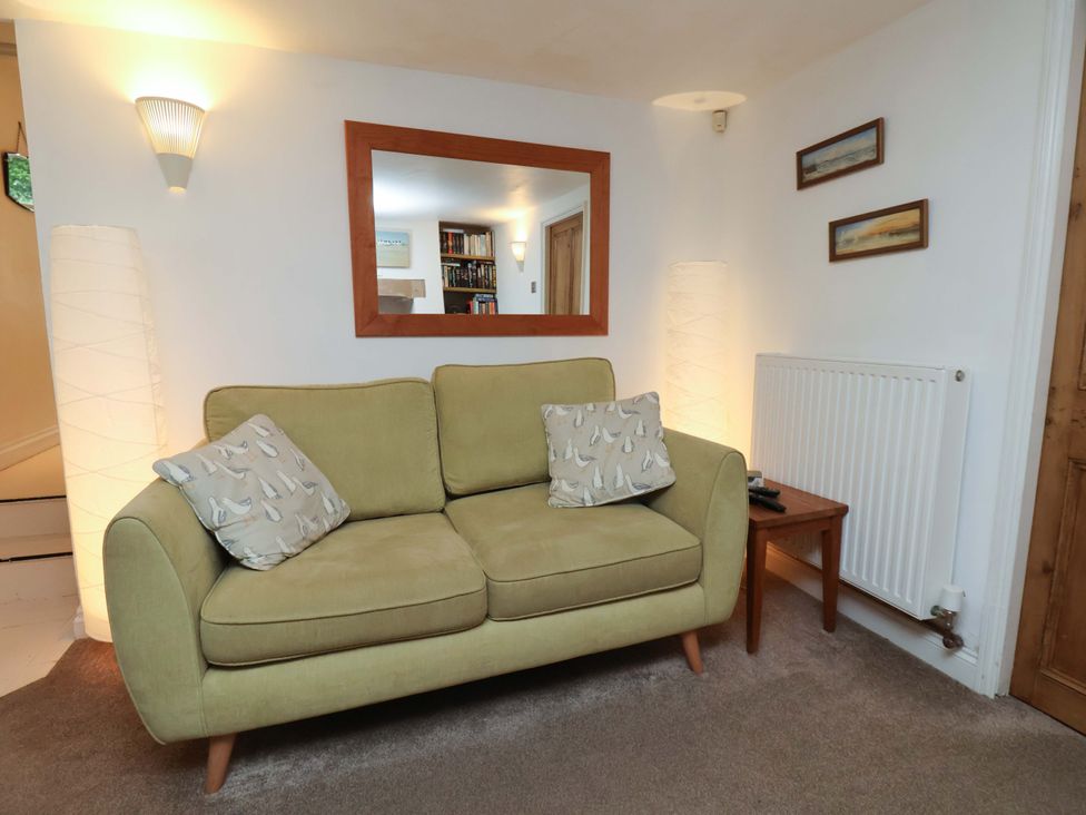 A living room with a sofa and a mirror at Damson Cottage in Whitby