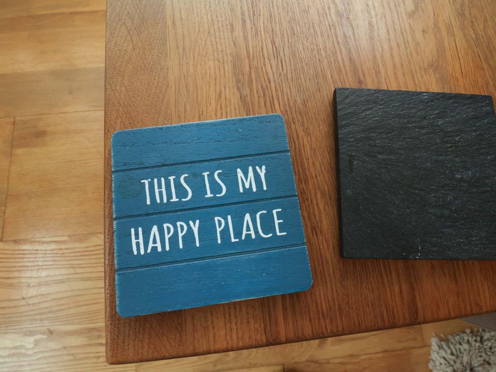 A blue coaster with text on a wooden table at Damson Cottage in Whitby