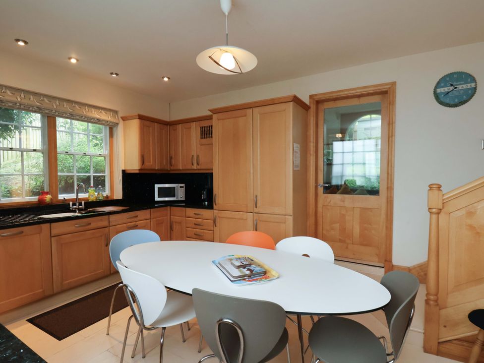 A kitchen with wooden cabinets and a round table at Damson Cottage in Whitby