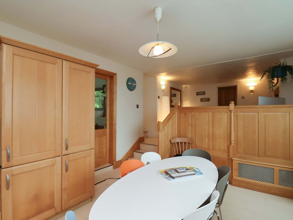 A kitchen with wooden cabinets and a round table at Damson Cottage in Whitby