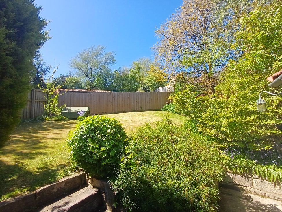 A garden with trees and grass at Damson Cottage in Whitby