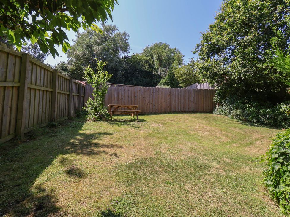 A garden with a bench and trees at Damson Cottage in Whitby