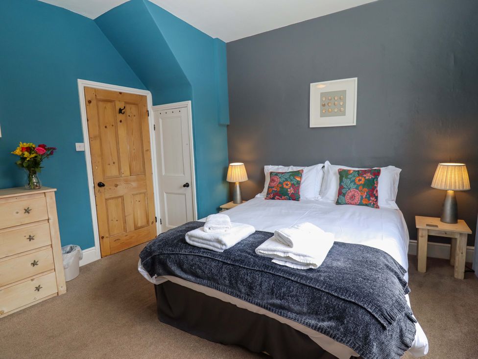 A bedroom with a bed and flowers on a dresser at West End House in Whitby