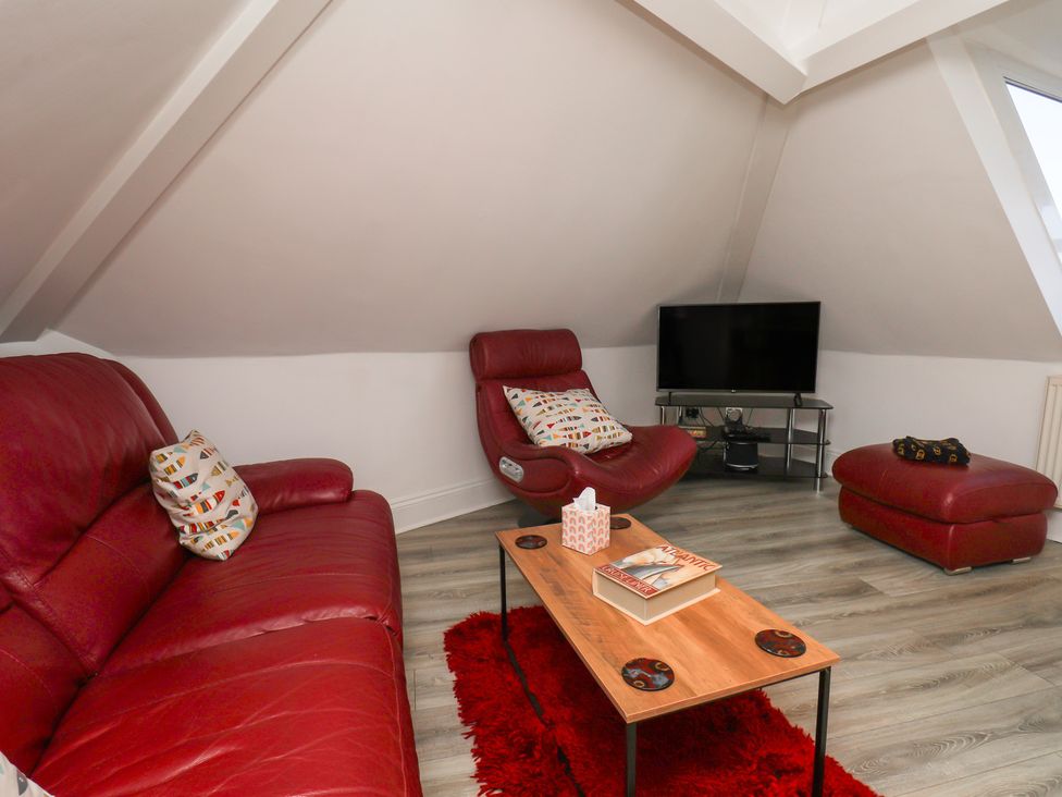 A living room with a red sofa and a television at Beachfront in Whitby