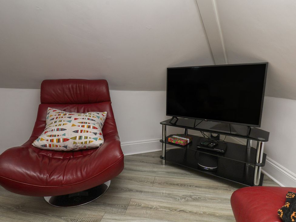 A snug room with a red chair and television at Beachfront in Whitby