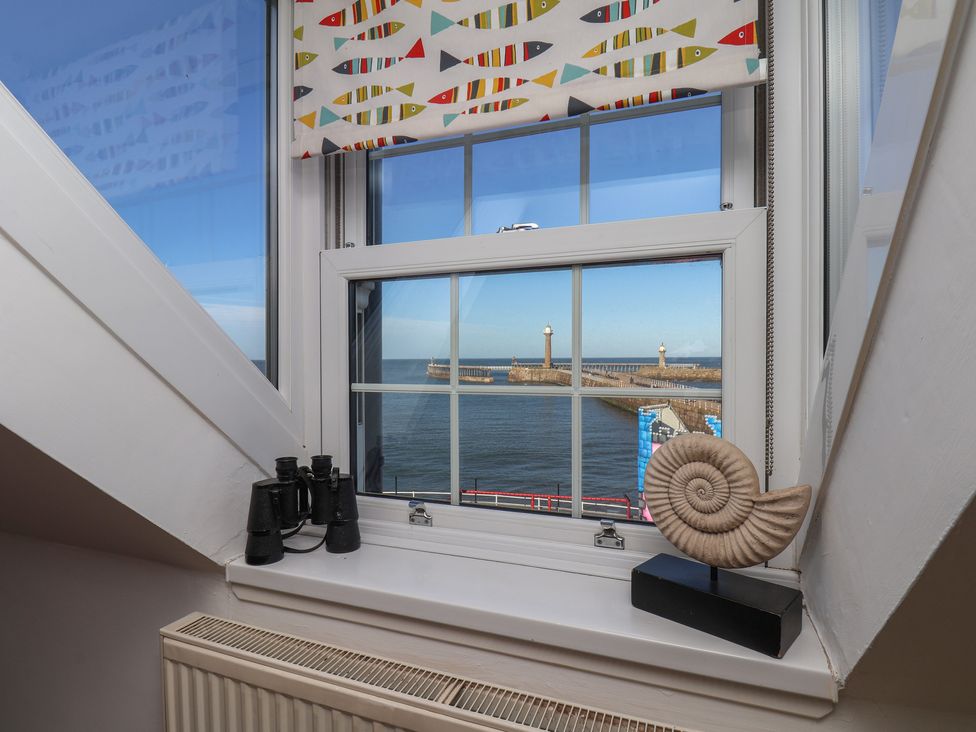 A view from a window with binoculars and a shell on a ledge at Beachfront in Whitby