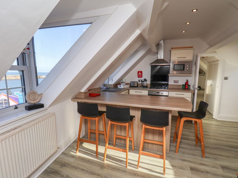 A kitchen with bar stools and modern appliances at Beachfront in Whitby