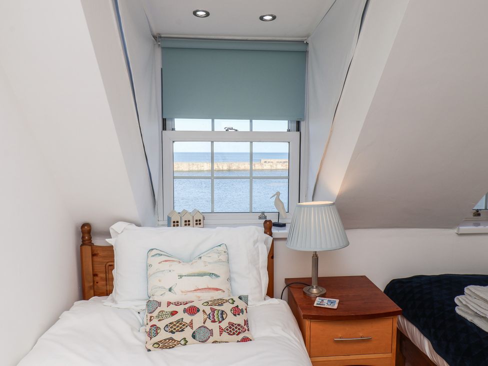 A bedroom with a bed and window view at Beachfront in Whitby