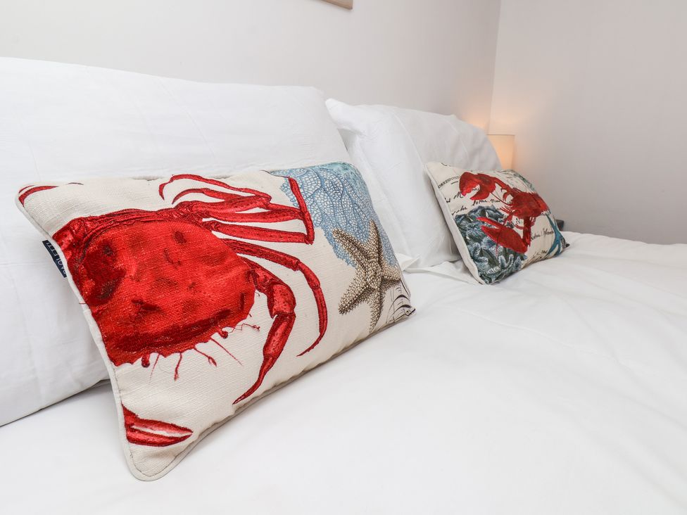 A bedroom with crab and starfish cushions on a bed at Beachfront in Whitby