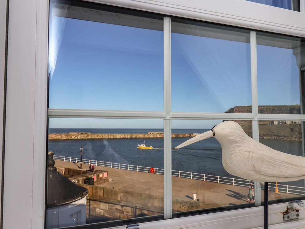 A window view with a bird figurine and a boat on the ocean at Beachfront Whitby