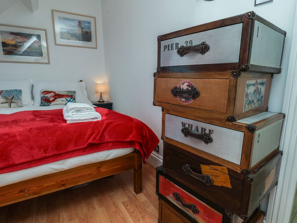 A bedroom with a bed, storage boxes, and bedside lamp at Beachfront Whitby