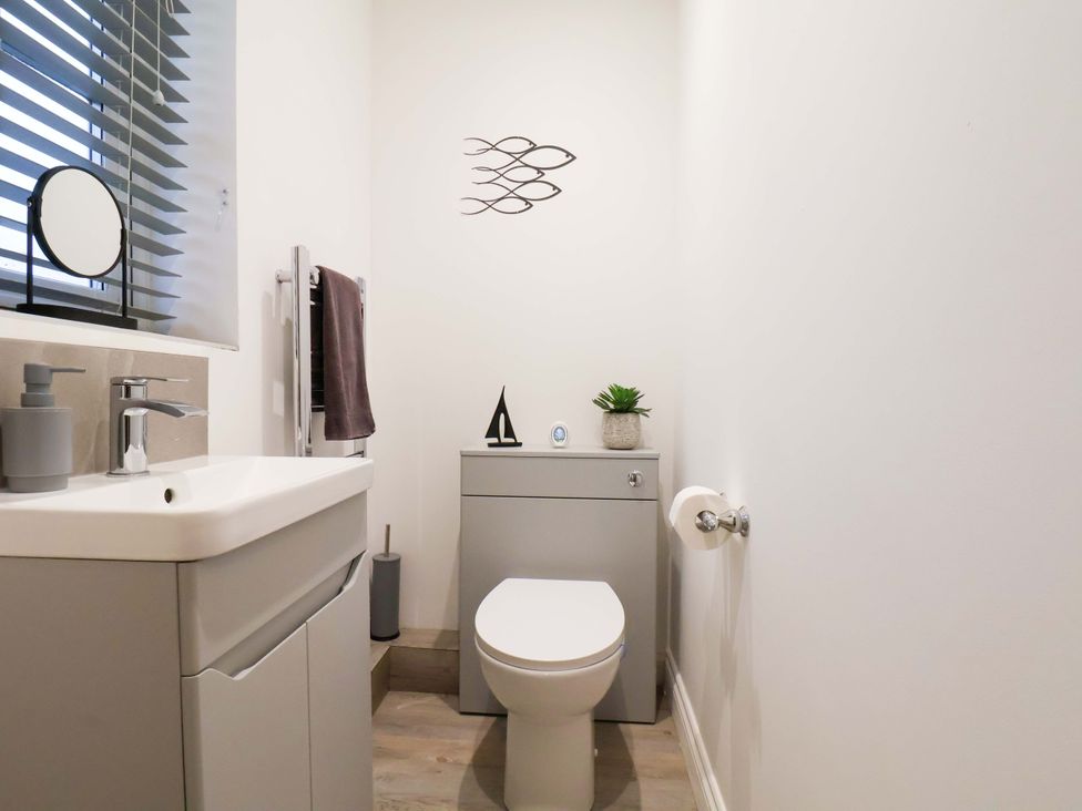 A bathroom with a sink, toilet and mirror at Bay Cottage The Bay - Filey