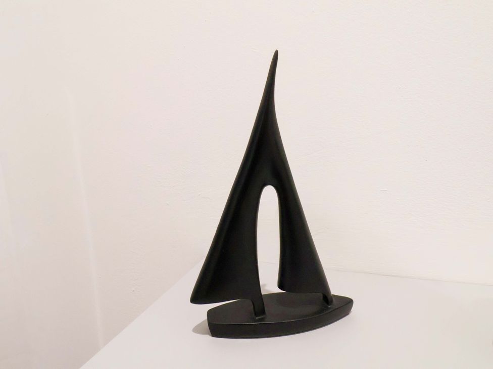 A black abstract sculpture resembling a sail on display