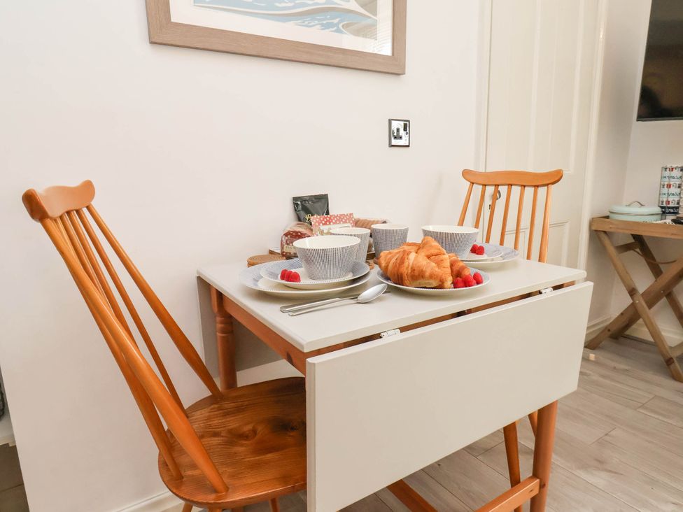 A small dining table with two wooden chairs set with plates bowls croissants and raspberries at The Riddle in Whitby