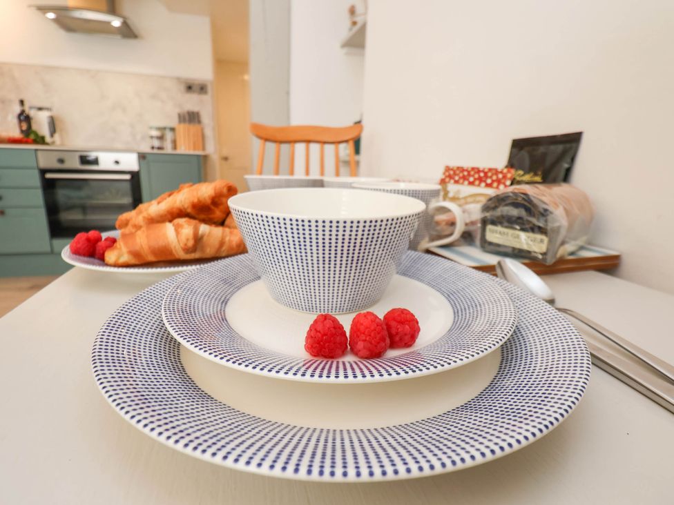 A kitchen table set with blue dotted plates cups croissants and raspberries at The Riddle in Whitby