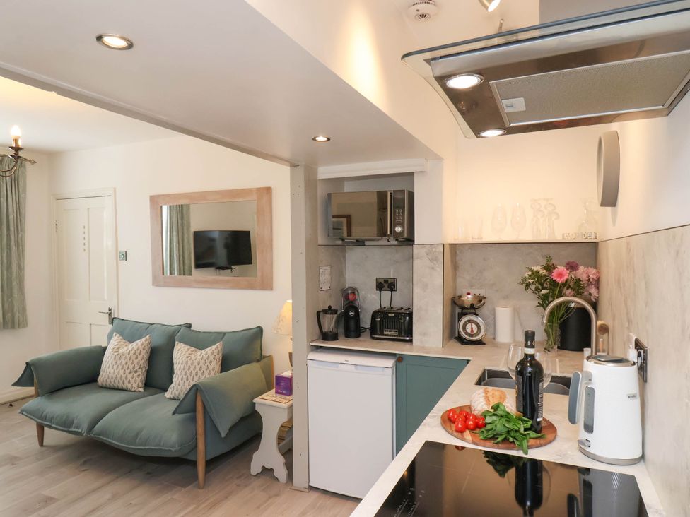 A kitchen area with countertop appliances and a living space with a sofa and wall-mounted TV at The Riddle in Whitby